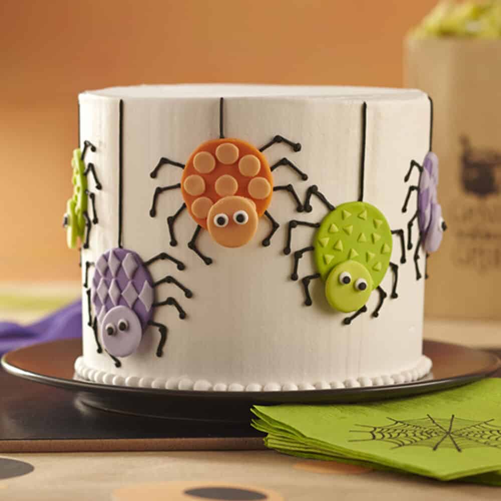 white cake with orange, green and purple spiders