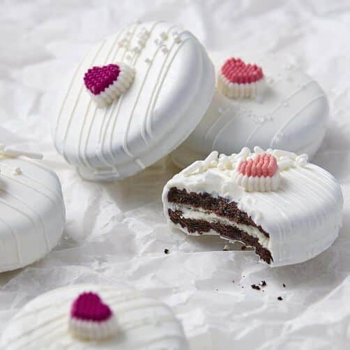 White candy Melts covered sandwich cookies with heart icing decoration