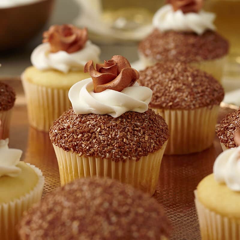 Cupcakes with copper colored sprinkles and a copper colored rose on top