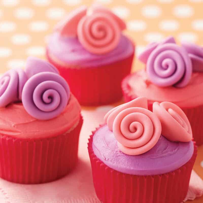 Pink and purple cupcakes topped with pink and purple fondant ribbon roses