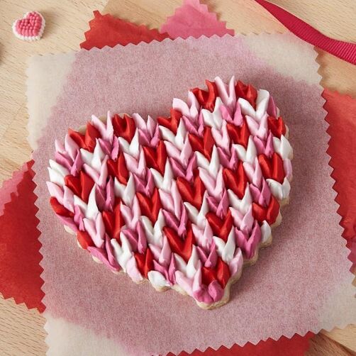 Heart-shaped cookie with red, white, and pink piped frosting design