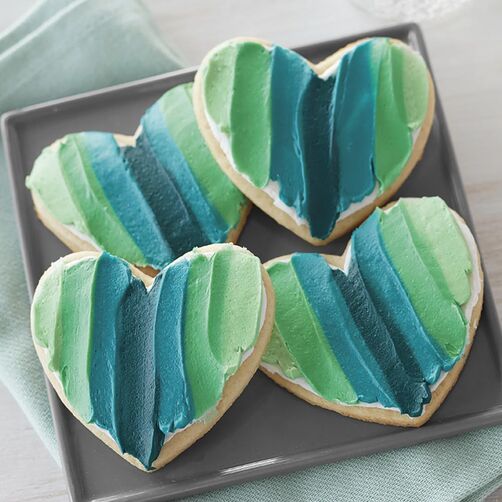 Spatula painted heart-shaped cookies with shades of blue and green icing