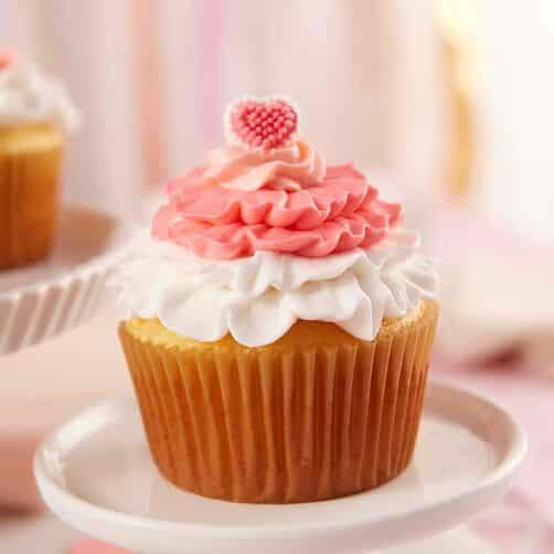 Valentine's Day cupcakes with pink and white ruffles and topped with a mini candy heart