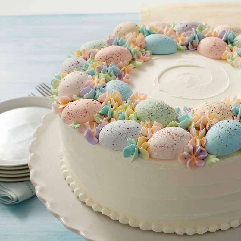 Cake topped with chocolate speckled pastel eggs and piped flowers