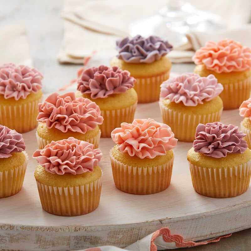 mini cupcakes decorated with a buttercream frosting carnation