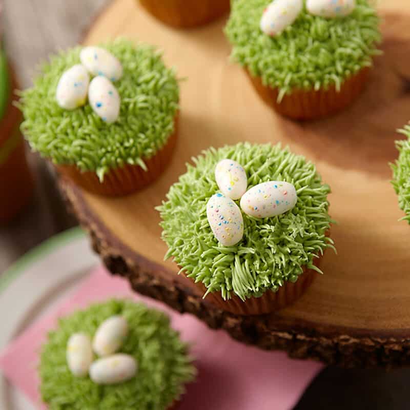 cupcakes topped with pipped green grass and speckled candy Easter eggs