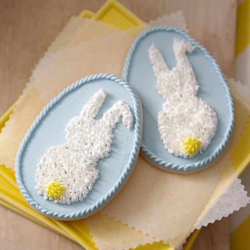 easter egg cookies with a piped easter bunny and tail in the center