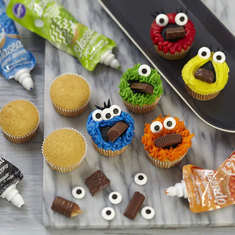 cupcakes decorated like monsters using icing, eyeballs and candies