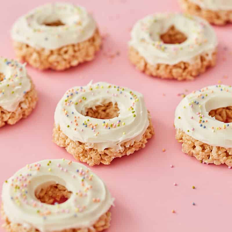 rice krispies shaped like donuts and decorated with white frosting and sprinkles