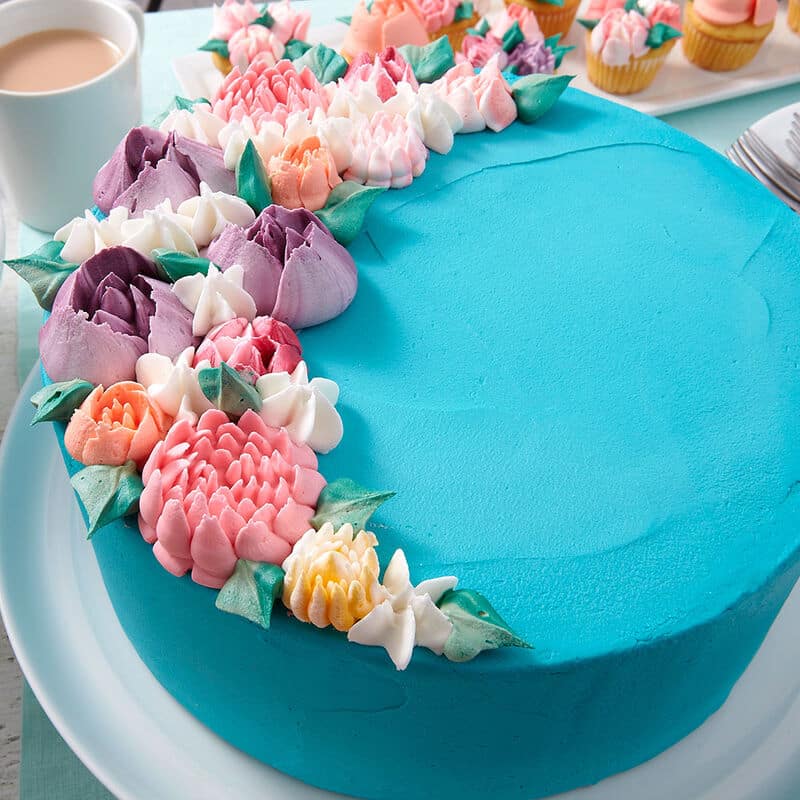 blue buttercream frosted cake with colorful buttercream blooms