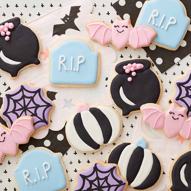 Pastel royal icing decorated Halloween cookies- black and white pumpkins, cauldrons, black and pink bats, purple spider webs and baby blue tombstones ,