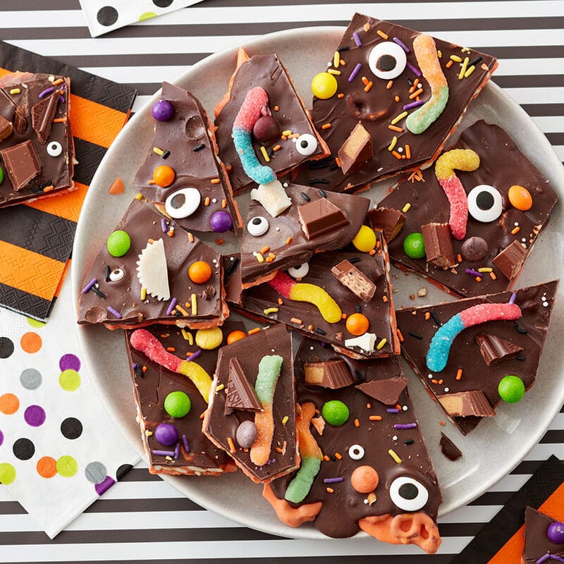 Candy bark featuring Halloween candy like gummy worms, chocolate bars, and candy eyeballs